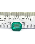 GIA certified 1.40 carat emerald-cut Colombian emerald with sparkling bluish-green color, next to a ruler.
