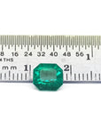 GIA certified 1.40 carat emerald-cut Colombian emerald with sparkling bluish-green color, next to a ruler.