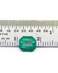 GIA certified 1.40 carat emerald-cut Colombian emerald with sparkling bluish-green color, next to a ruler.