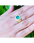 Men's 18K yellow gold ring with a medium-deep green emerald in a full bezel setting, worn on a hand.