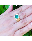 Men's 18K yellow gold ring with a medium-deep green emerald in a full bezel setting, worn on a hand.