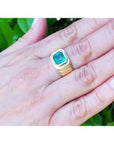 Men's 18K yellow gold ring with a medium-deep green emerald in a full bezel setting, worn on a hand.