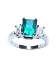 This three stone emerald engagement ring with side natural emerald cut diamonds, is crafted in 18k white gold.