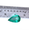 2.77 carat GIA certified pear cut Colombian emerald with vivid deep bluish-green hue, next to a ruler.
