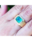 Men's 18K yellow gold ring with a rectangular, medium-deep green emerald in a full bezel setting.