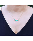 14K gold necklace with five round medium green Colombian emeralds in elegant basket settings.