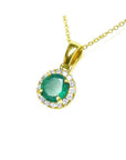 Round cut deep green Colombian emerald necklace with halo diamonds in 14k yellow gold.