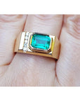 A 14k yellow gold ring for men with a bezel set natural emerald and accent diamonds.