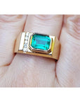 A 14k yellow gold ring for men with a bezel set natural emerald and accent diamonds.