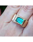 Men's 14K yellow gold ring with an east-west emerald-cut Colombian emerald and channel-set diamonds.