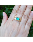 Men's 14K yellow gold ring with an east-west emerald-cut Colombian emerald and channel-set diamonds.