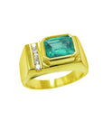 Men's gold ring with a natural emerald bezel set and small diamonds on a topside profile view.