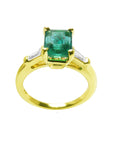 A 14k yellow gold ring with a natural colombian emerald on a white background.