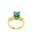 A 14k yellow gold ring with a natural colombian emerald on a white background.