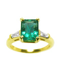 A front top view of an emerald gold ring with tapered baguettes side diamonds on a white background.