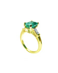 The half side of a gold emerald ring with a side diamond and band profile on a white background