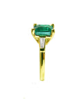 The side profile of this emerald ring displays the top gemstone a tapered bague and band side.