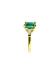 The side profile of this emerald ring displays the top gemstone a tapered bague and band side.