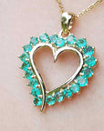 Heart-shaped pendant round colombian emerald stones on a light pink background