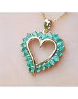 Heart-shaped pendant round colombian emerald stones on a light pink background