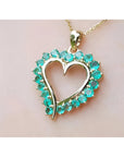 Heart-shaped pendant round colombian emerald stones on a light pink background