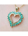 Heart-shaped pendant round colombian emerald stones on a light pink background