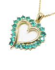 Gold heart-shaped pendant with emerald stones on a white background