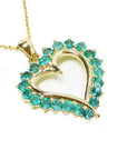 Gold heart-shaped pendant with round cut natural emeralds on a right topside view.