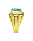 Gold ring for man with a bezel set natural colombian emerald on a white background.