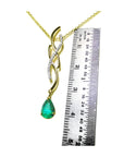 14K yellow gold twisted slider necklace with a pear-shaped emerald pendant and diamond accents, shown with a ruler.