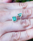 Natural emerald stud earrings displayed on a hand