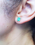 Close-up of an ear wearing a genuine emerald stud earring.