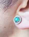 Close-up of an ear wearing halo diamond emerald stud earring.