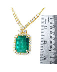 3.43 ct emerald halo necklace with natural diamonds on a 14K yellow gold chain, shown next to a ruler.