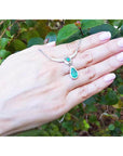 1.67 ct pear emerald necklace with diamonds in 14K white gold on a hand.