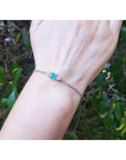14K white gold bracelet with a rectangular Colombian emerald and diamond accents on a wrist.