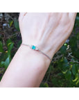 14K white gold bracelet with a rectangular Colombian emerald and diamond accents on a wrist.