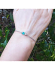 14K white gold bracelet with a rectangular Colombian emerald and diamond accents on a wrist.