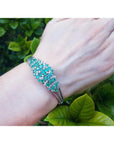 14k white gold bangle bracelet with prong-set round Colombian emeralds and natural diamonds on a wrist.