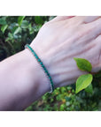 Natural Colombian emeralds tennis bracelet, round cut, prong set in 14K gold, on a wrist.