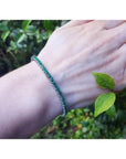 Natural Colombian emeralds tennis bracelet, round cut, prong set in 14K gold, on a wrist.