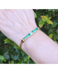 14K gold bracelet with five vibrant bluish-green emeralds and sparkling diamonds on a woman's wrist.