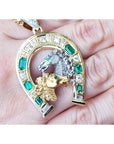 18K yellow gold horseshoe pendant with emeralds, diamonds, and two horse heads.