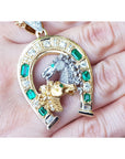 on hand displaying an emerald horseshoe pendant and natural diamonds crafted in 18k yellow gold lucky jewelry
