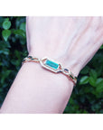 Bracelet with a genuine emerald on a wrist against a blurred green background