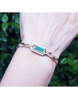 14K yellow gold bracelet with a vibrant emerald-cut Colombian emerald and accent diamonds on a wrist.