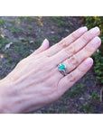 Oval emerald ring in 18K white gold with a decorative bridal band on a hand.