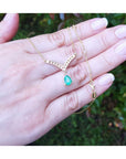 1.01 carat pear cut emerald necklace with accent diamonds set in a 14K yellow gold V-chevron design.