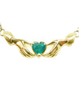 14k yellow gold Claddagh necklace with a heart-shaped emerald gemstone on a white background