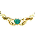 14k yellow gold Claddagh necklace with a heart-shaped emerald gemstone on a white background